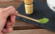 Ceremoniální matcha - kvalitní práškový japonský zelený čaj matcha v plechové dóze - detail prášku na bambusové lžičce chashaku